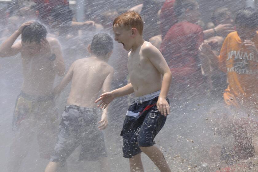 FILE - In this June 9, 2006, file photo, kids from a day camp get soaked by the the fire department at Tyler Junior College in Tyler, Texas. The U.S. has seen a string of COVID-19 outbreaks tied to summer camps in recent weeks in Texas, Illinois, Florida, Missouri and Kansas, offering what some fear could be a preview of the upcoming school year. (Brad Smith/Tyler Morning Telegraph via AP, File)