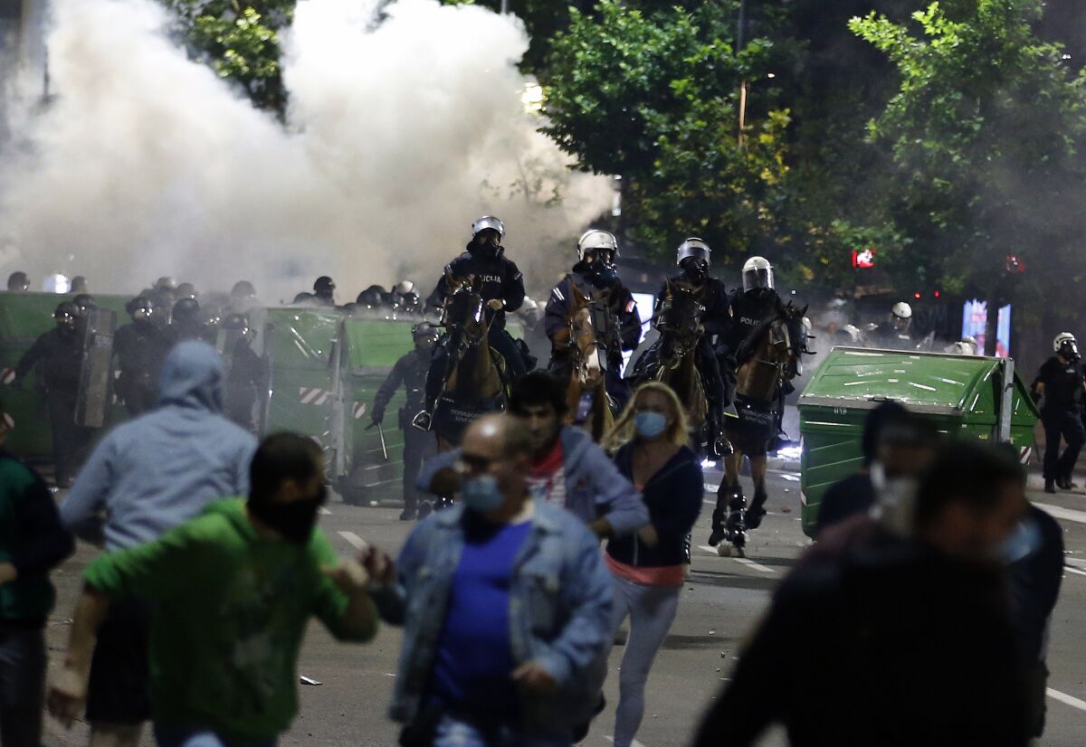 Sebian police officers disperse protesters in front of Serbian parliament building in Belgrade, Serbia, Wednesday, July 8, 2020. Thousands of people protested the Serbian president's announcement that a lockdown will be reintroduced after the Balkan country reported its highest single-day death toll from the coronavirus Tuesday. (AP Photo/Darko Vojinovic)