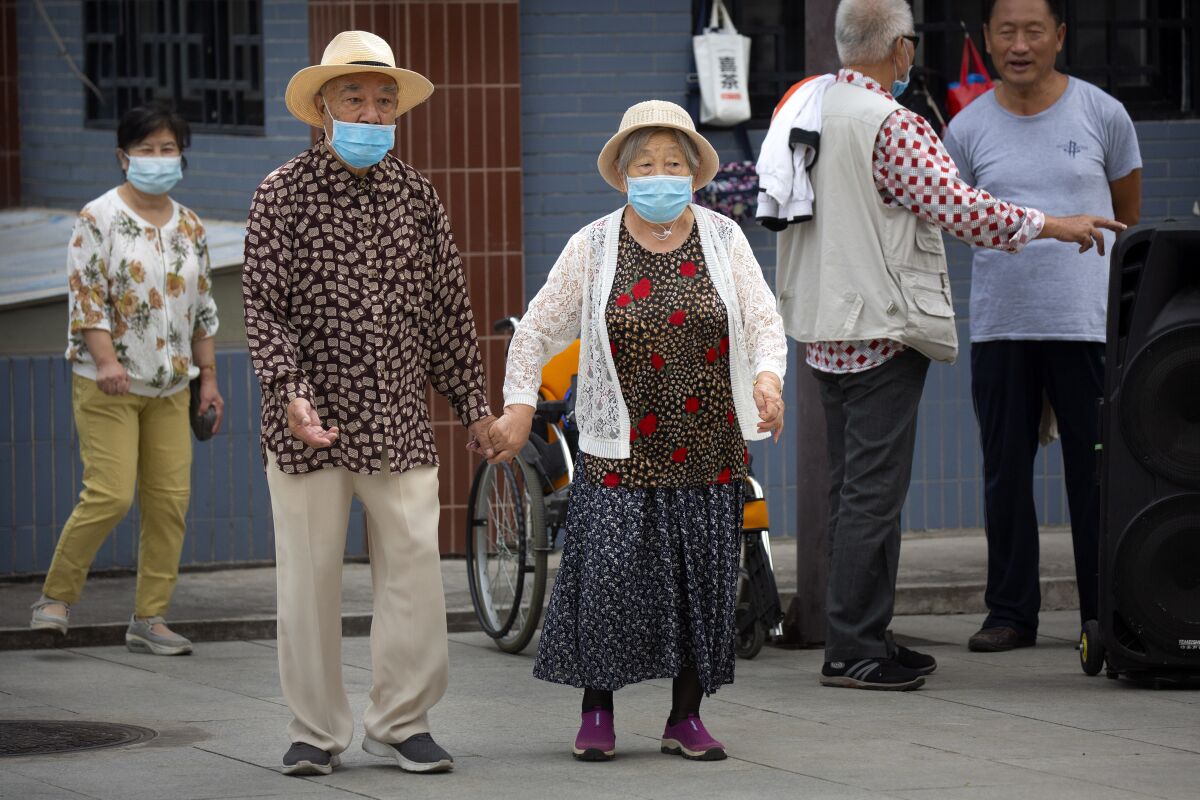 An elderly couple wearing face masks to protect against the coronavirus walks at a public park in Beijing, Saturday, Sept. 12, 2020. Even as China has largely controlled the outbreak, the coronavirus is still surging across other parts of the world. (AP Photo/Mark Schiefelbein)