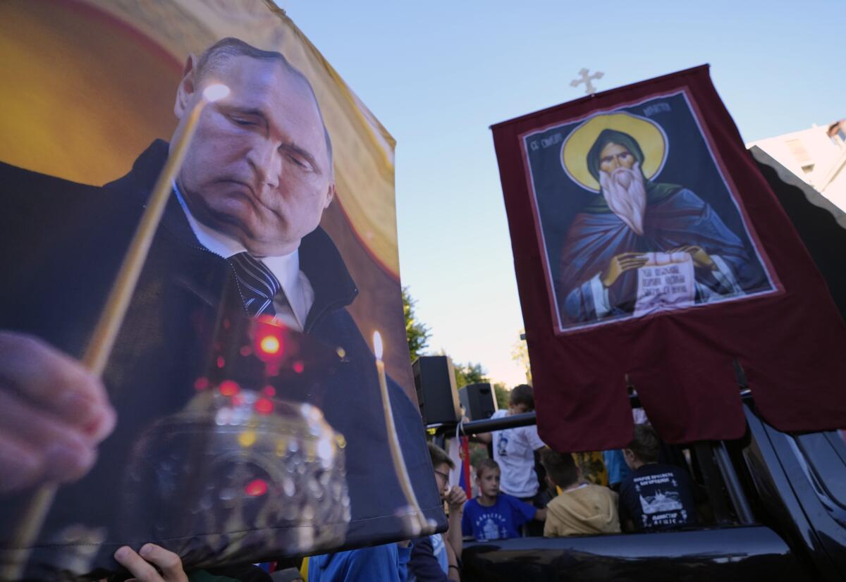 People hold icons and a picture of Russian President Vladimir Putin during a protest against the international LGBT event Euro Pride in Belgrade, Serbia, Sunday, Sept. 11, 2022. Thousands of opponents of a pan-European LGBTQ event planned for this week in Belgrade marched through the Serbian capital on Sunday despite an announced ban of Europe's largest annual gay gathering. (AP Photo/Darko Vojinovic)