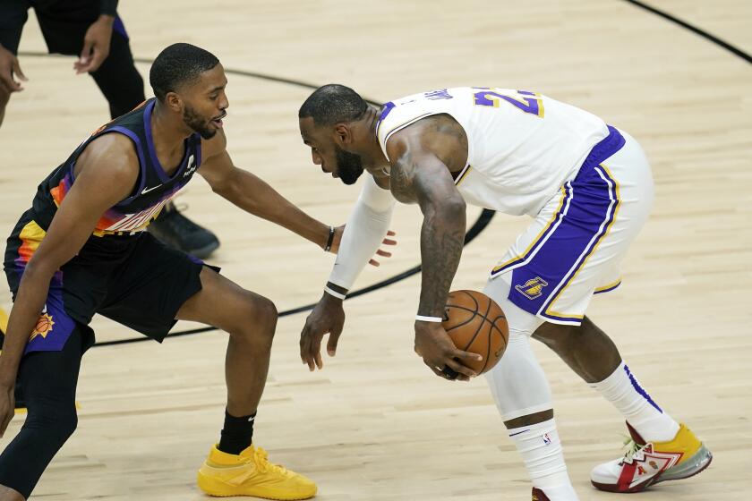 Los Angeles Lakers forward LeBron James, right, dribbles the ball against Phoenix Suns forward Mikal Bridges, left, during the first half of Game 1 of their NBA basketball first-round playoff series Sunday, May 23, 2021, in Phoenix. (AP Photo/Ross D. Franklin)