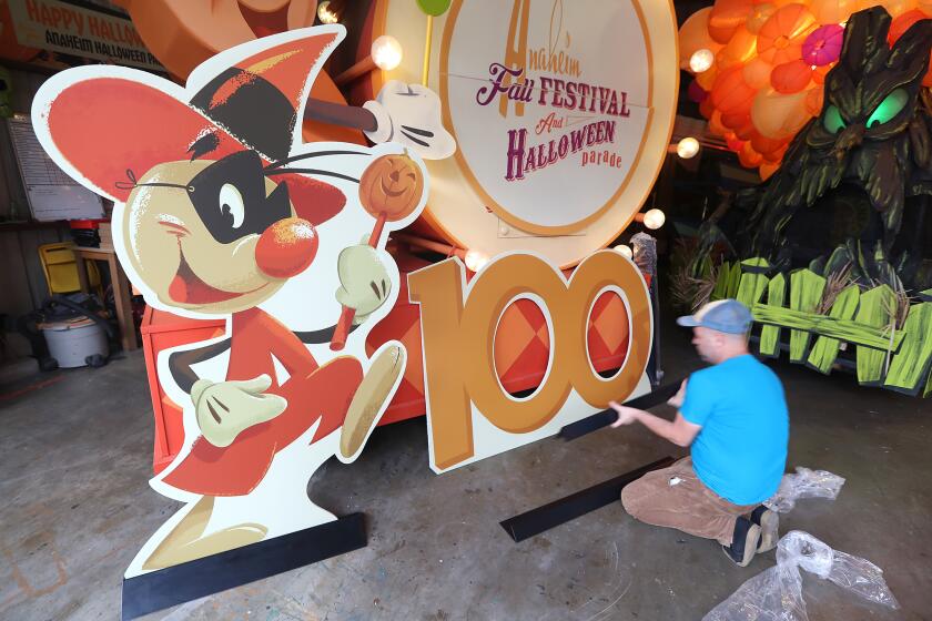 Artist Jody Daily adds support stands to the "100" sign on a float in preparation for the Anaheim Halloween Parade which celebrates its 100th anniversary this October.