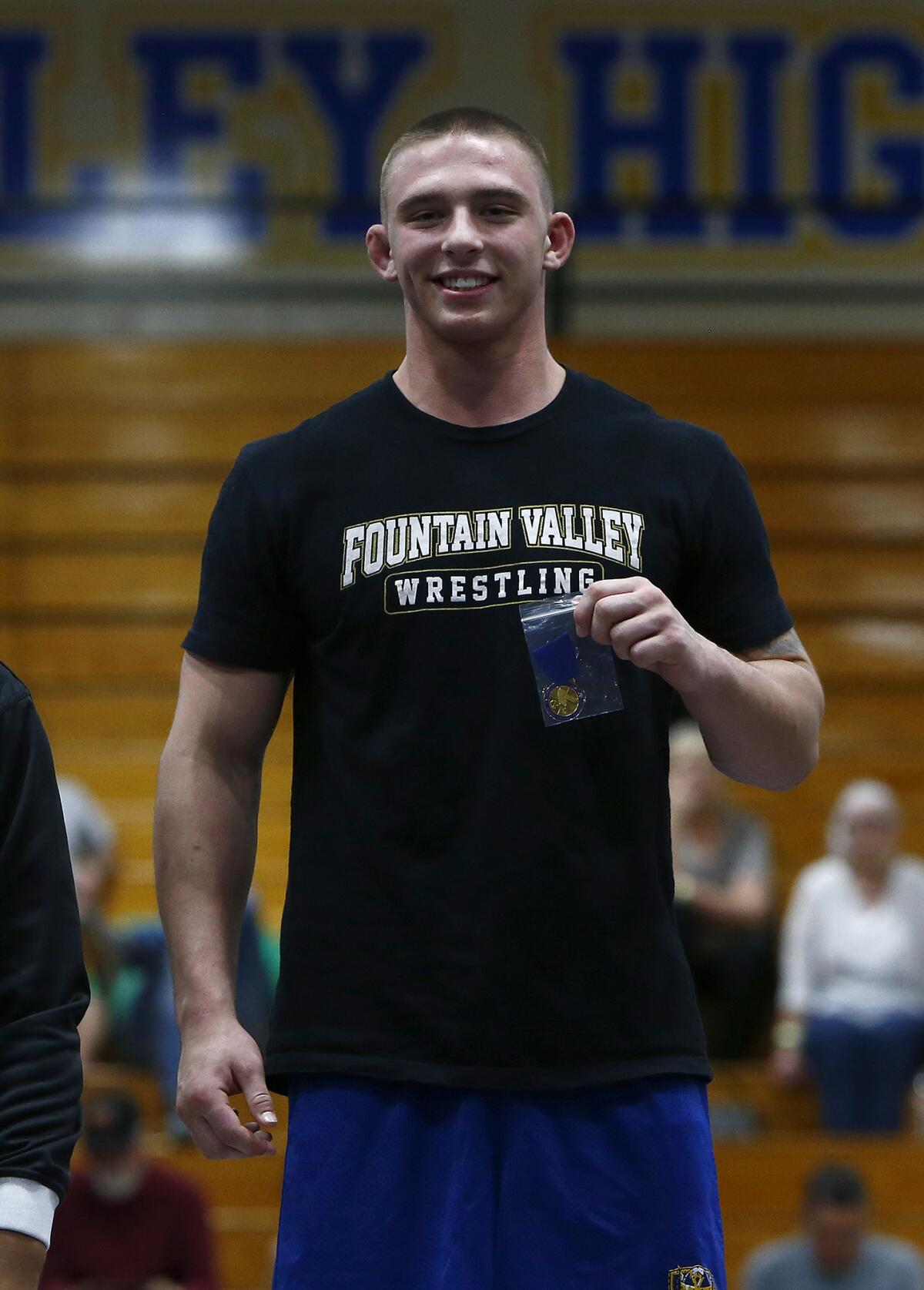 Fountain Valley's TJ McDonnell holds his first-place medal as he stands on the podium among the 182-pound finalists.