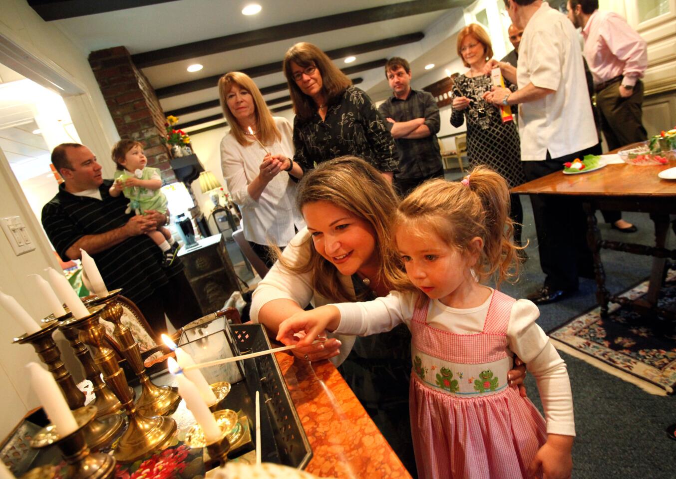 Havi Wolfson-Hall lights candles with her daughter Ellie before the Passover Seder at Ron and Susie Wolfson's home in Encino.