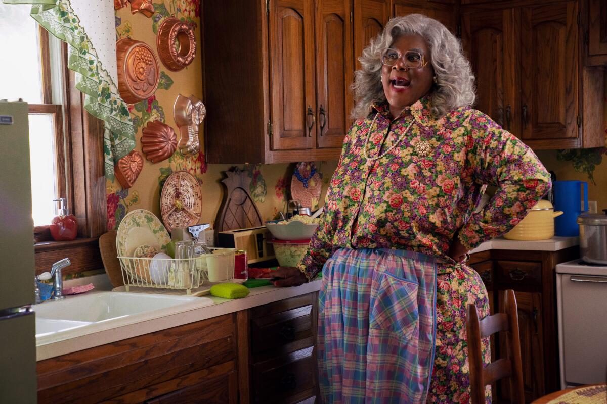 Tyler Perry in drag as Madea stands in a kitchen