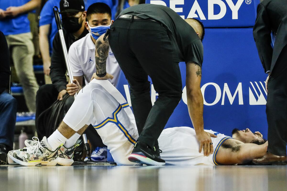 UCLA guard Jaime Jaquez Jr. is tended to by trainer Tyler Lesher after taking a bad fall.