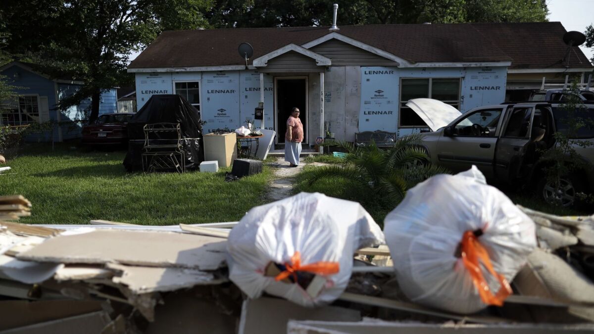 Griselda Perez looks out from behind a wall of flood-damaged debris as the family cleans out their flooded home following Hurricane Harvey in Houston.