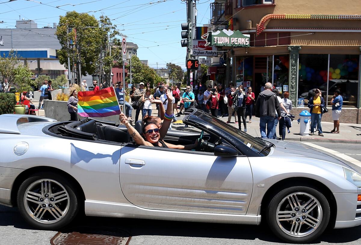 Same-sex marriage supporters wave pride flags from a car Wednesday as they drive by the corner of Market and Castro in San Francisco.