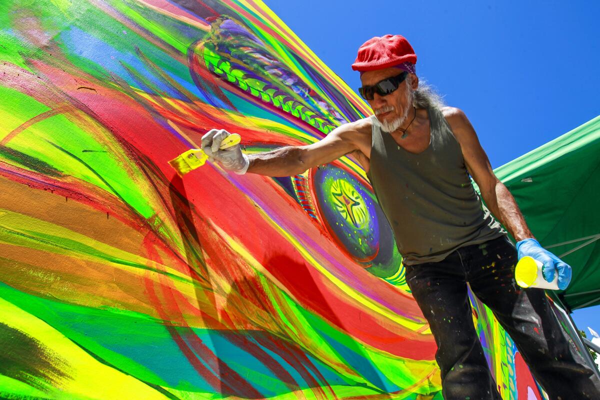 Chicano artist and muralist Mario Torero paints in the interactive mural area.