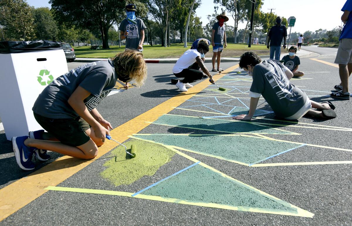 Silas Newcott, 14 of Costa Mesa, left, paints a crosswalk at Arlington Drive during Love Costa Mesa 2020 in October.