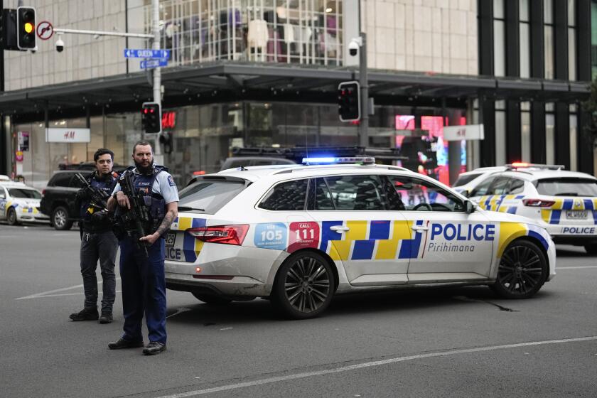 Armed New Zealand police officers stand at a road block in the central business district following a shooting 
