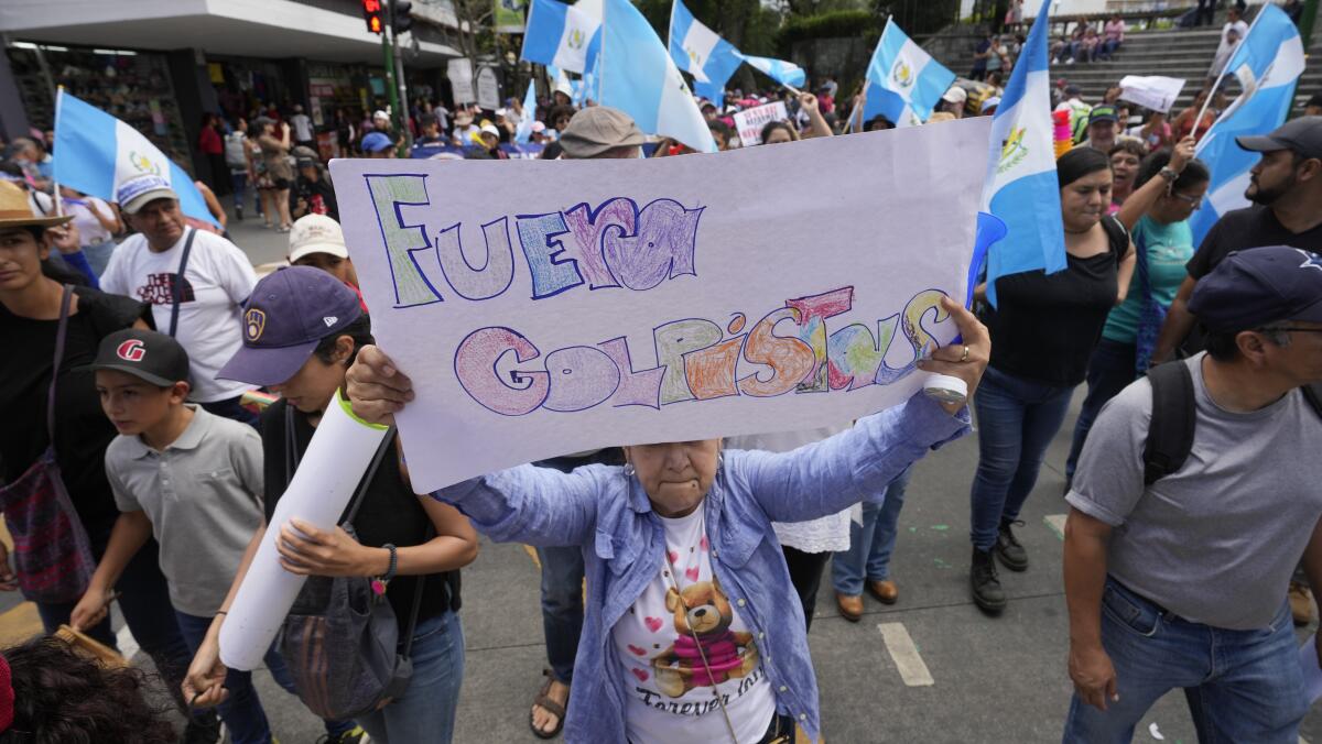 Una mujer sostiene un cartel con un mensaje que dice en español: "Fuera golpistas", 