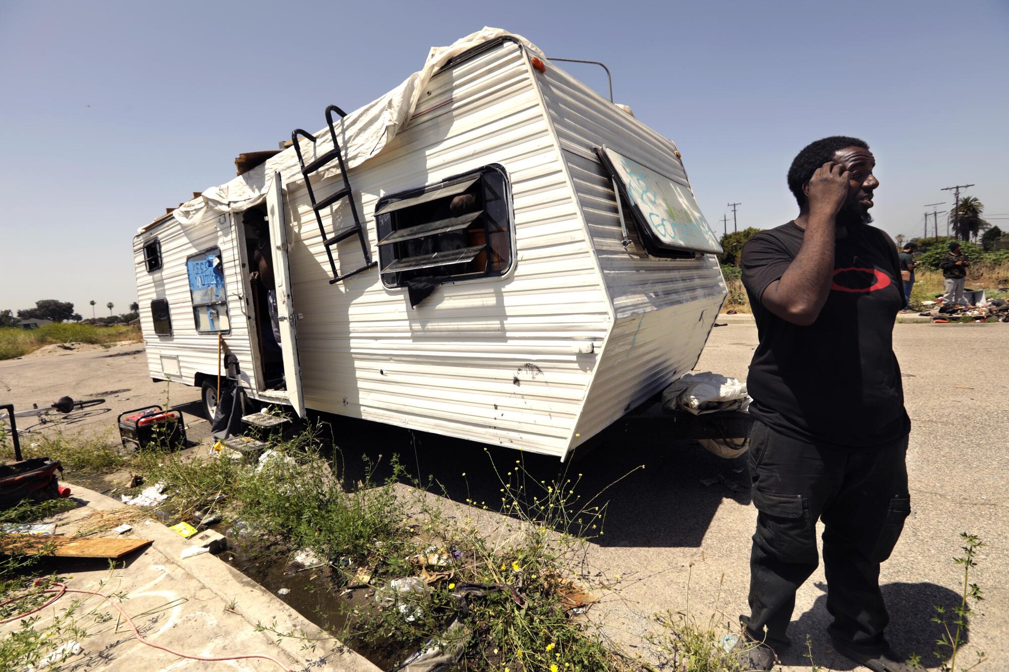 Asa Grissett stands near his mobile home that is parked along a road on a portion of a10-acre vacant lot in Watts. 