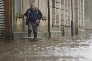 A man walks through flood water on Canal Quay in Newry Town, Co Down, which has been swamped by floodwater as the city's canal burst its banks amid heavy rainfall, Wednesday Nov. 1, 2023. Dozens of businesses were engulfed in the floods, with widespread damage caused to buildings, furnishings and stock. (Brian Lawless/PA via AP)