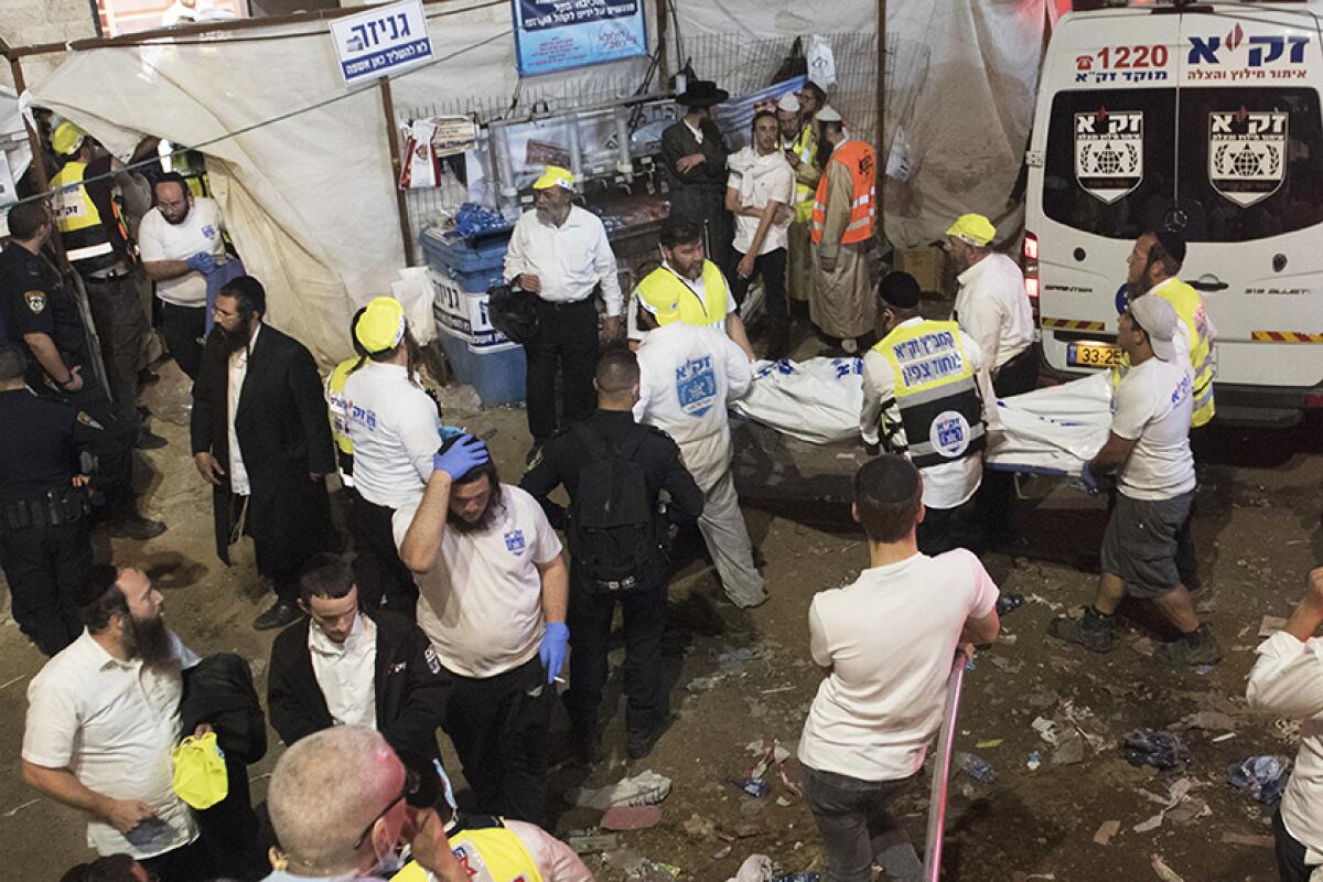 Israeli officials carry the body of a stampede victim.