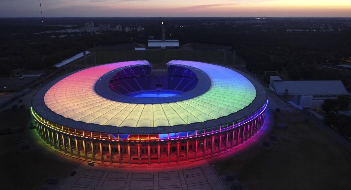 The sun sets behind the rainbow-illuminated Olympic  