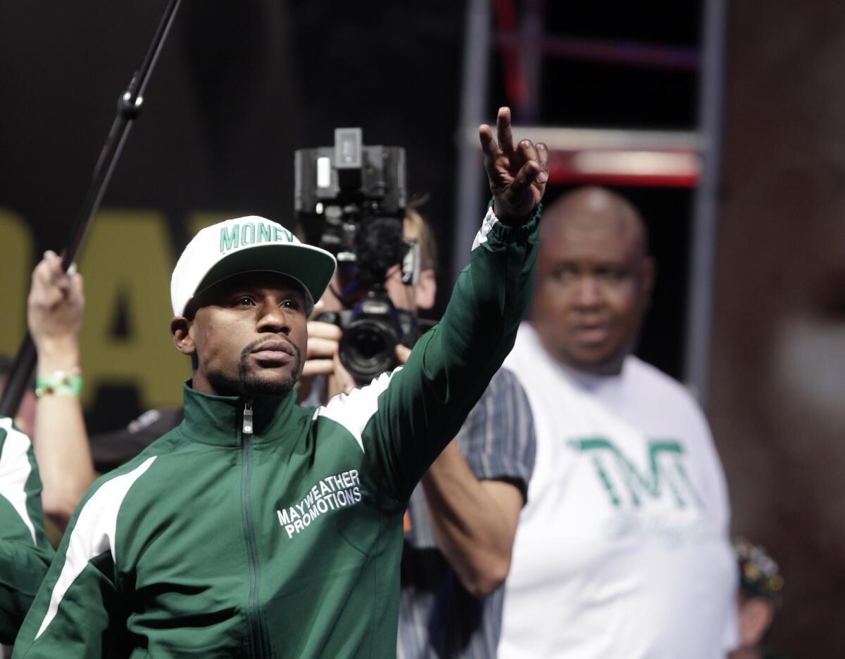 Floyd Mayweather Jr. waves to fans as he arrives on stage for his weigh-in Friday ahead of his bout with Marcos Maidana at the MGM Grand. Mayweather will defend his WBC/WBA welterweight and super-welterweight titles Saturday night.