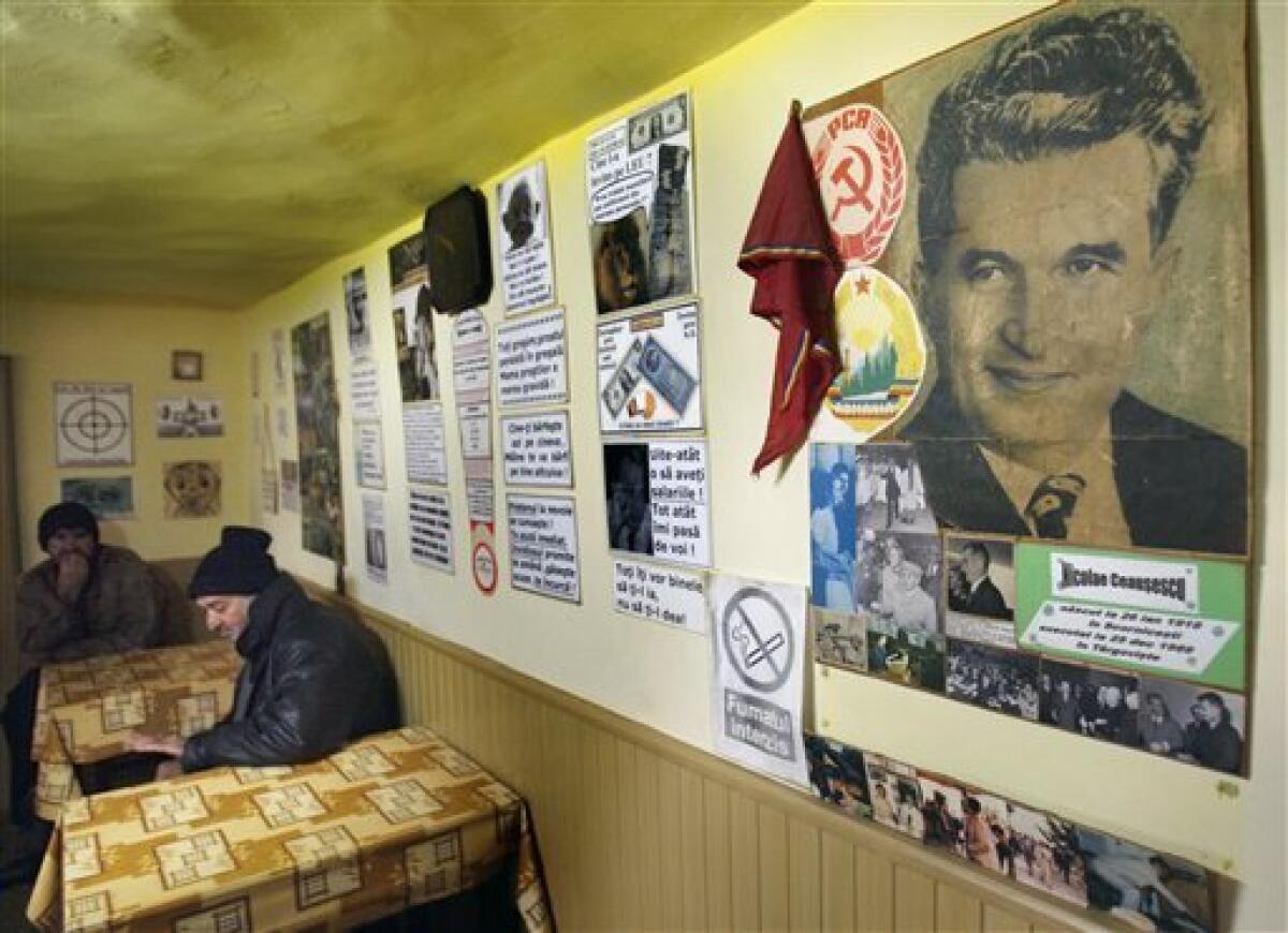 In this picture taken on Dec. 15, 2009, men sit at tables in a village bar bearing the picture of dictator Nicolae Ceausescu on the wall along with other communist era symbols in Scornicesti, southern Romania, the birth place of Ceausescu. This week Romanians commemorate 20 years since communist dictator Nicolae Ceausescu fled Bucharest during a popular uprising on Dec. 22, 1989, after ruling Romania for 25 years. Ceausescu was executed together with his wife Elena on Dec. 25, 1989.More than a thousand people are reported to have lost their lives during the Romanian revolution.(AP Photo/Vadim Ghirda)