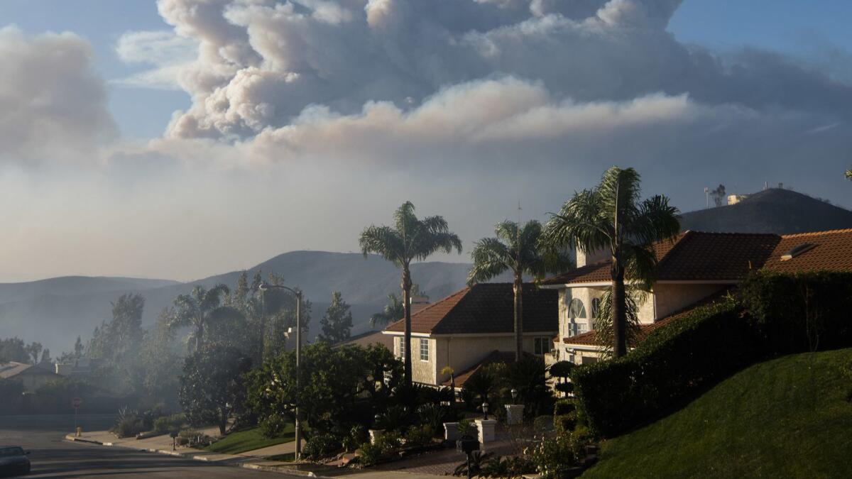 A smoke column from the Woolsey fire rises over homes in Oak Park on Friday.