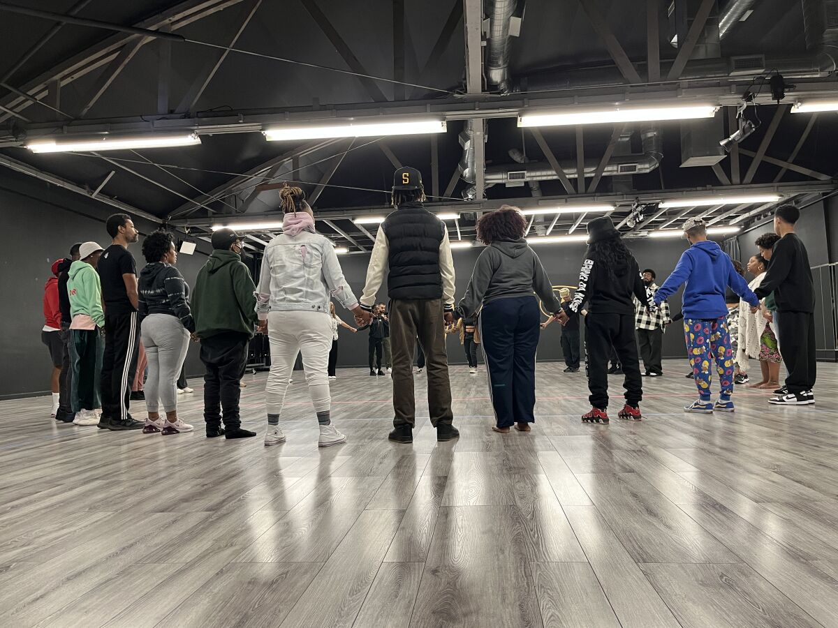 Dancers and activists hold hands at Mihran K. Studios while planning a protest performance at Frieze Los Angeles.