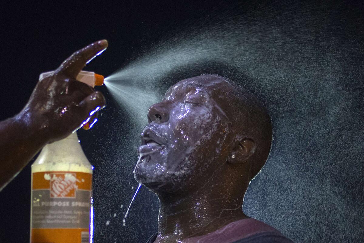 A man is doused with milk and sprayed with mist after being hit by an eye irritant from security forces trying to disperse demonstrators protesting against the shooting of Brown in Ferguson