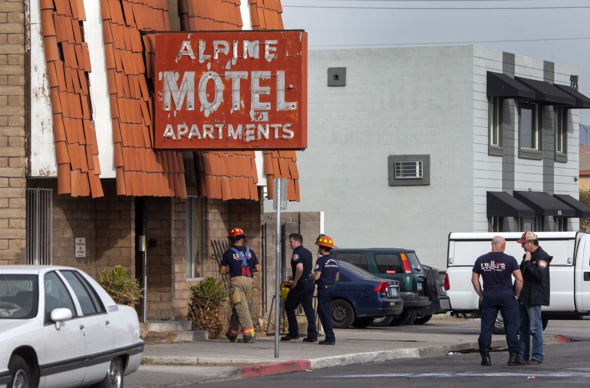 Firefighters outside of a building with a red sign that reads Alpine Motel Apartments.