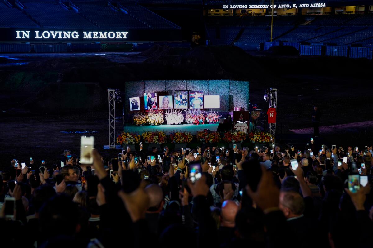 People hold up cell phones with lights on, during a celebration of life ceremony at Angel Stadium on Monday to honor the lives of John, Keri and Alyssa Altobelli, who were among the nine killed in a helicopter crash that also claimed the lives of Lakers legend Kobe Bryant and his daughter Gianna.