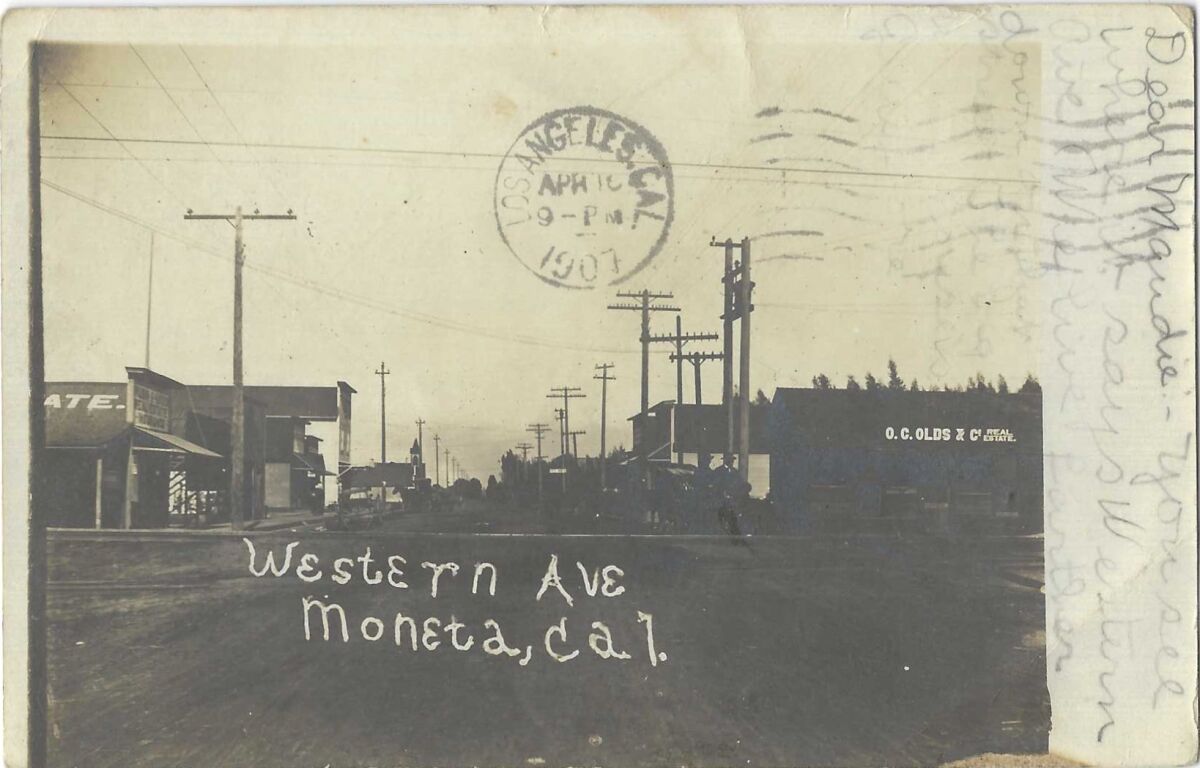 Black and white image shows a street scene. Text reads: 