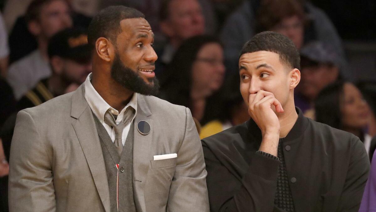 Injured Lakers LeBron James and Kyle Kuzma watch the game against the Philadelphia 76ers from the bench on Tuesday at Staples Center.