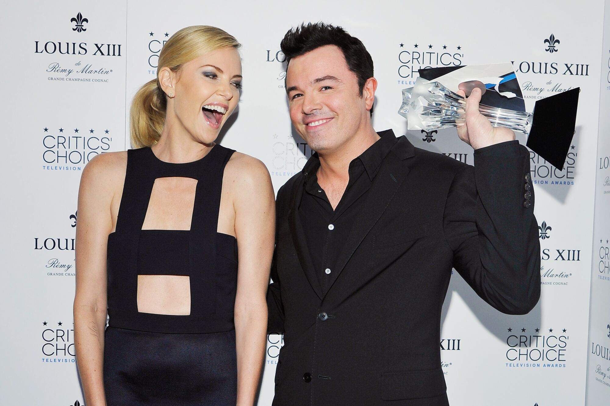 Actress Charlize Theron with Seth MacFarlane, holding an award.