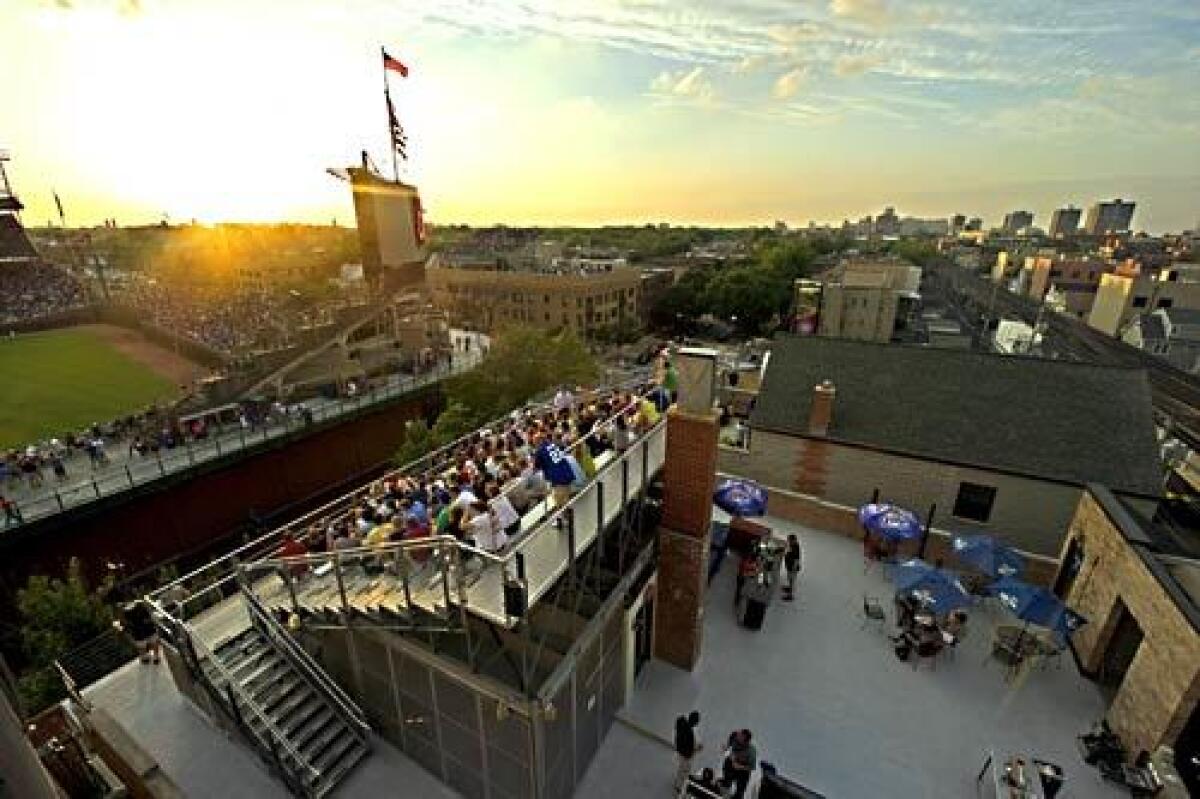 The sun sets on Wrigley Field and the rooftop fans in the neighborhood.