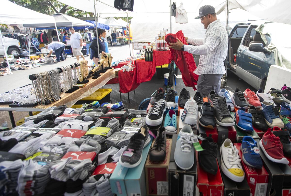 A vendor organizes his products at an outdoor swap meet.