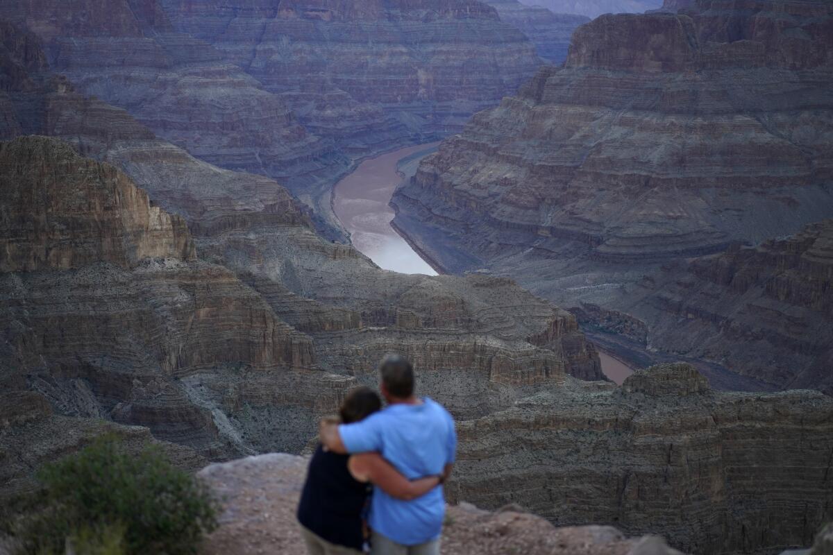A couple embraces as the Colorado River flows through the Grand Canyon on the Hualapai reservation Monday, Aug. 15, 2022, in northwestern Arizona. Officials said Tuesday, Aug. 16, 2022, there will be less water available next year from the river that serves 40 million people in the West and Mexico and observers say a reckoning is still coming for the growing region. (AP Photo/John Locher)