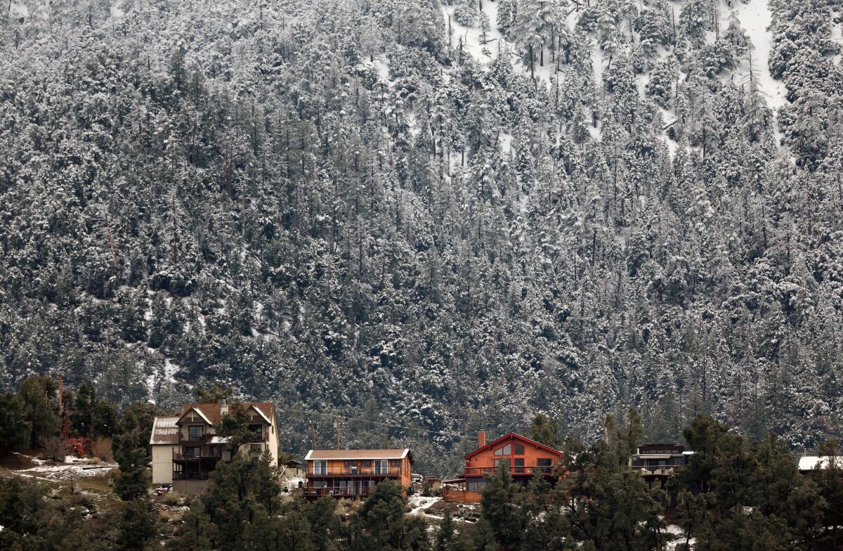 A view of cabins along snow-covered mountains.