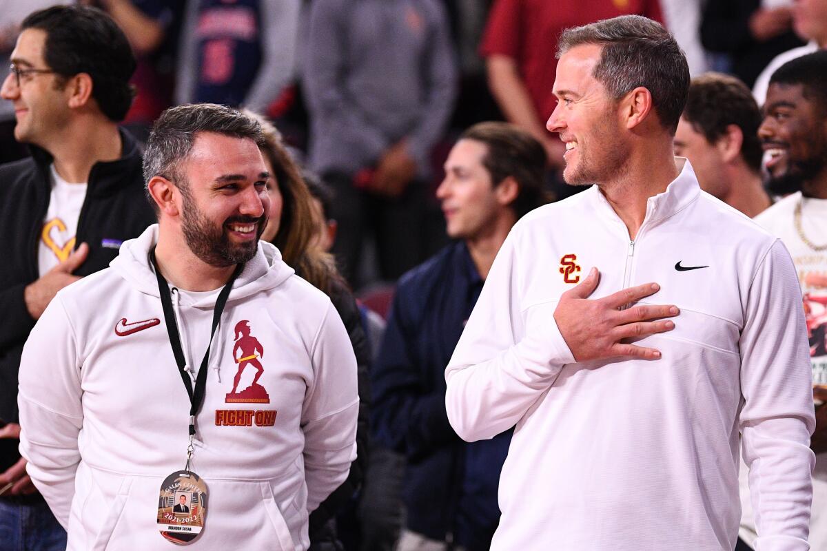 USC football coach Lincoln Riley shares a laugh with Brandon Sosna at a game.