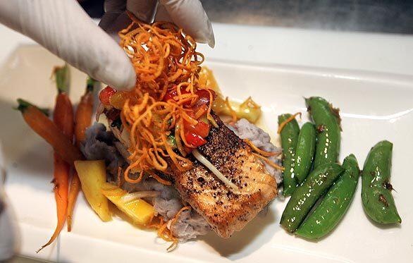 Diaz puts the finishing touches on a salmon dish. The Pacific Grille executive chef designs the menu, directs a staff of eight and prepares meals for more than 100 customers every day.