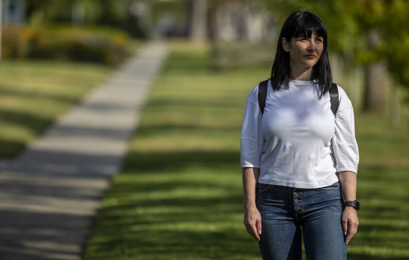 A woman stands next to a sidewalk path.