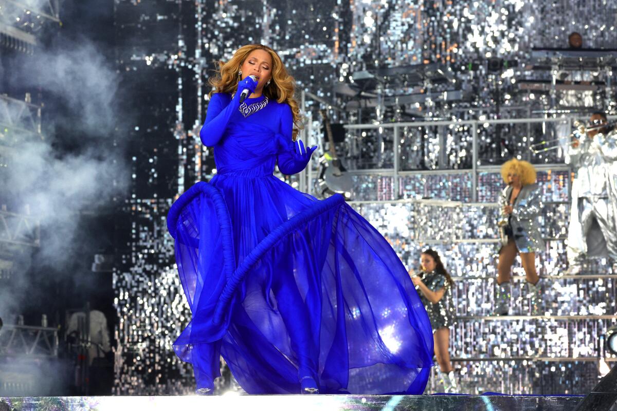 A woman in a blue dress sings into a microphone.