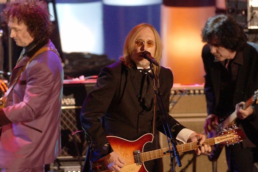 Tom Petty, center, and the Heart Breakers, perform after being inducted at the Rock and Roll Hall of Fame induction ceremony Monday, March 18, 2002, at New York's Waldorf Astoria. (AP Photo/Ed Betz)