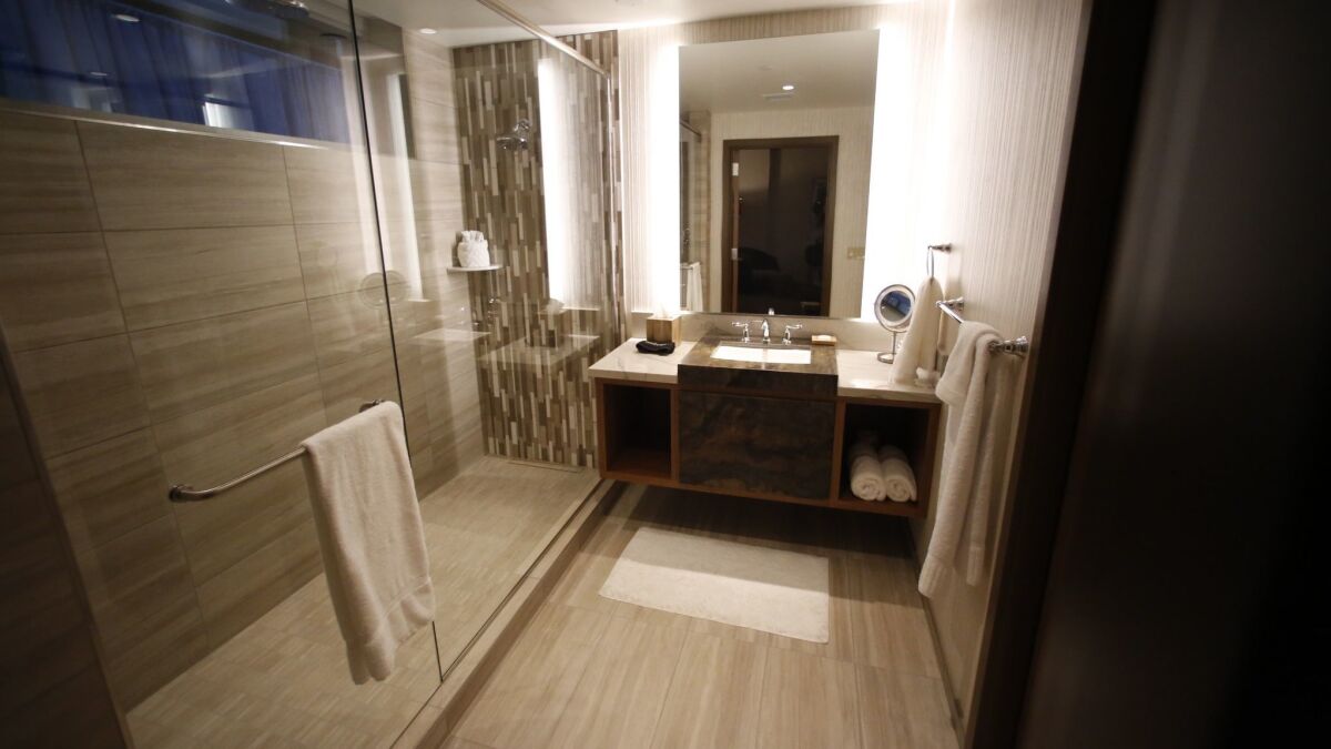 The bathroom of the mock suite features an oversized shower with two rain shower heads, stone finishes and a large separate water closet.