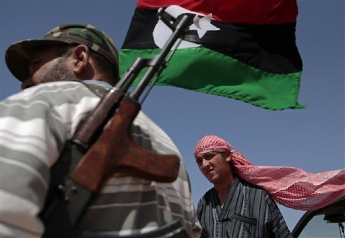 Libyan rebel fighters Omar Hussein, left, and Aaron Isa, right, stand guard under a rebel flag at the southern front line of the city of Misrata, Libya Thursday, June 9, 2011. On Wednesday pro-Gadhafi forces renewed their shelling near the western city of Misrata, killing 10 rebel fighters and on Thursday NATO airstrikes rattled the Libyan capital with clusters of bombing runs believed to have targeted the outskirts of Tripoli. (AP Photo/Luis Hidalgo)