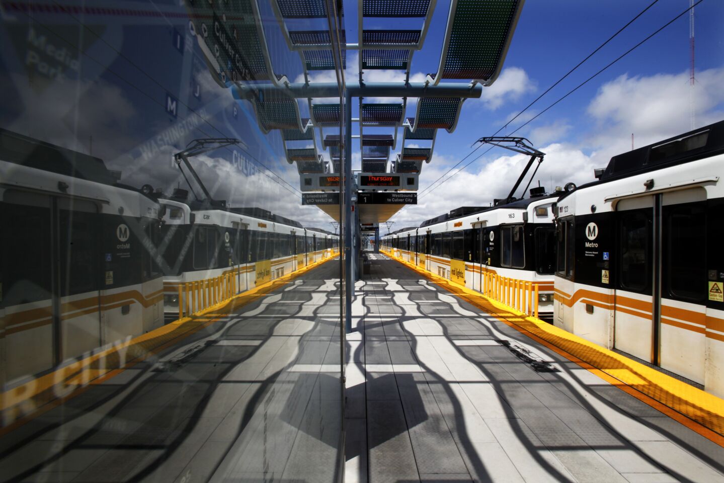 The newest Expo Line trains are reflected on a glass wall at the La Cienega Station after making several practice runs on April 26, 2012. The Expo Line runs between Los Angeles and the Westside and cost $930 million to complete. REVIEW: Lackluster Expo Line reflects Metro's weak grasp of design