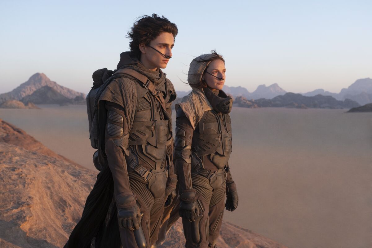 A man and a woman in an alien planet's desert landscape.