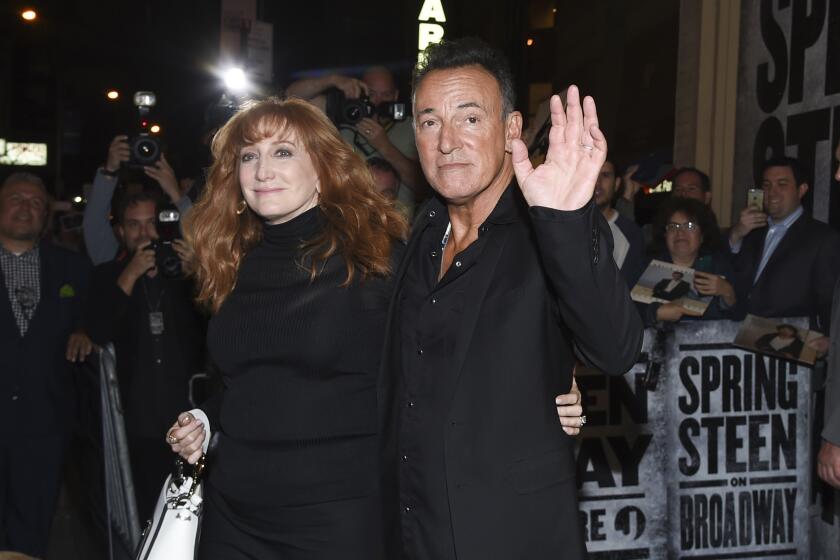 Patti Scialfa and Bruce Springsteen, both dressed in black, hug while greeting fans at opening night of his Broadway show