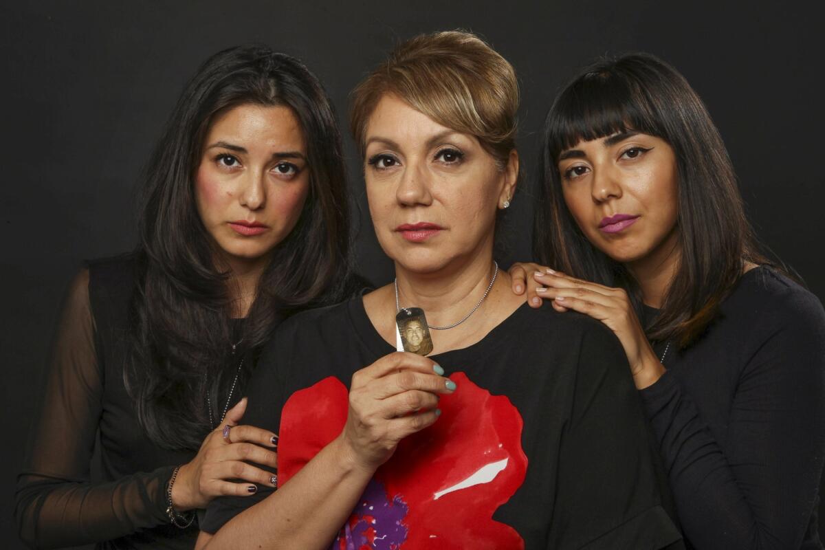 Diana Cruz holds a dog tag with a dog tag picture of her son Air Force military policeman Mike Cruz, who died by suicide, with her daughters Morgan Cruz, left, and Marrisa Cruz.