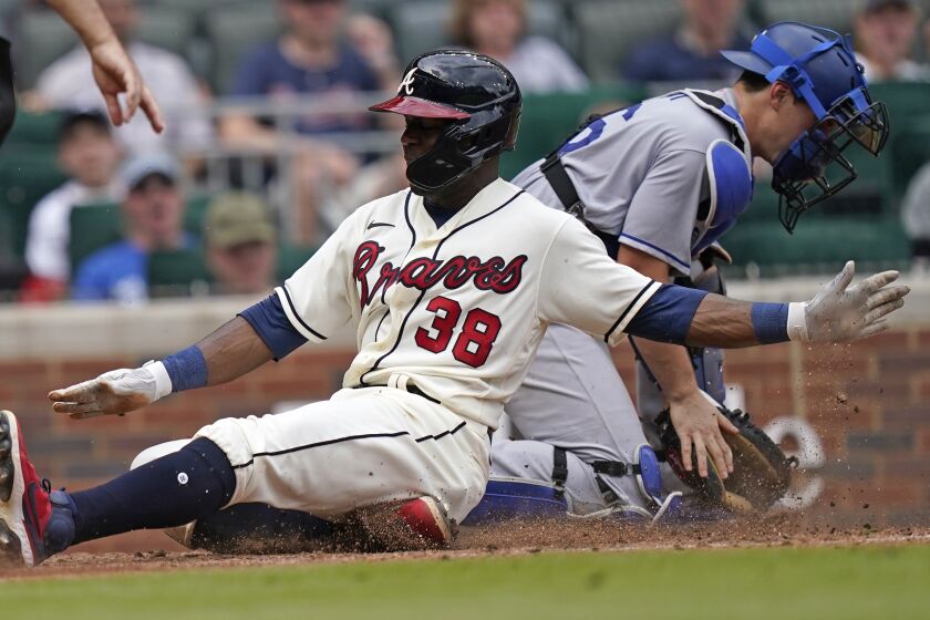 Atlanta Braves' Guillermo Heredia (38) scores ahead of the throw to Los Angeles Dodgers catcher Will Smith.