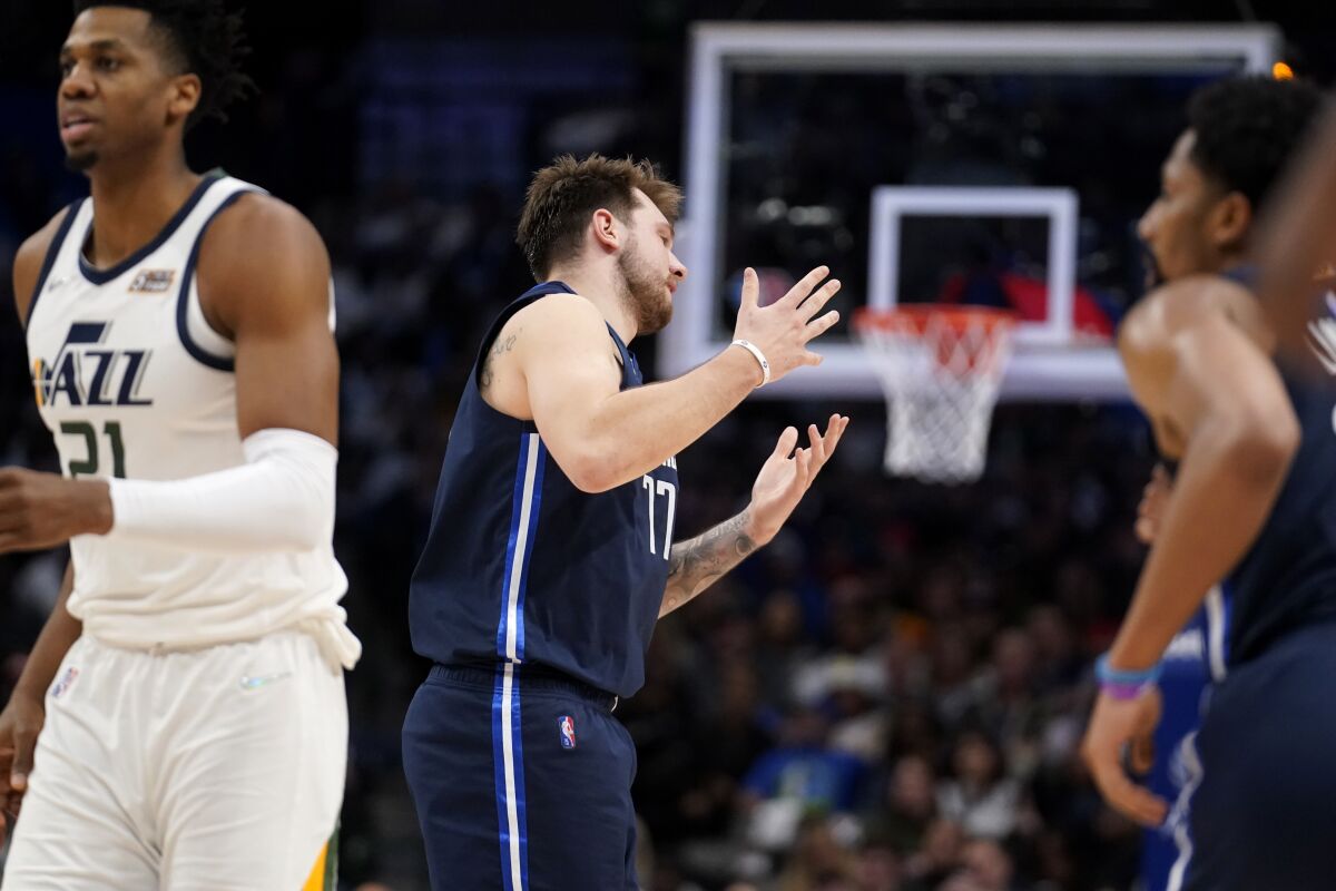 Utah Jazz center Hassan Whiteside (21) stands by as Dallas Mavericks guard Luka Doncic, center, celebrates after sinking a basket in the second half of an NBA basketball game in Dallas, Monday, March, 7, 2022. (AP Photo/Tony Gutierrez)