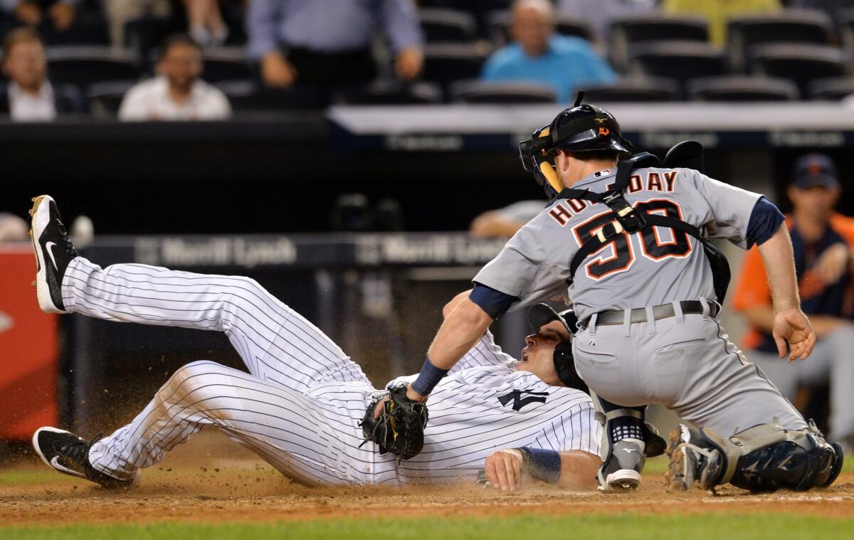 The Yankees' Mark Teixeira is tagged by the Tigers' Bryan Holaday at home plate. The play was challenged by the Yankees and Texeira, initially called out, was ruled safe.