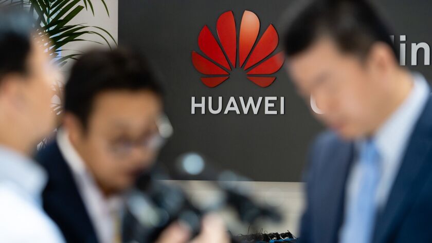 Visitors stand at Huawei's booth Monday during the Hannover Industry Fair in Germany.