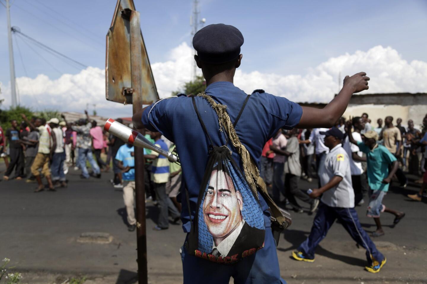 A police officer keeping watch on demonstrators in Bujumbura, Burundi, carries a bag with the portrait of President Obama.